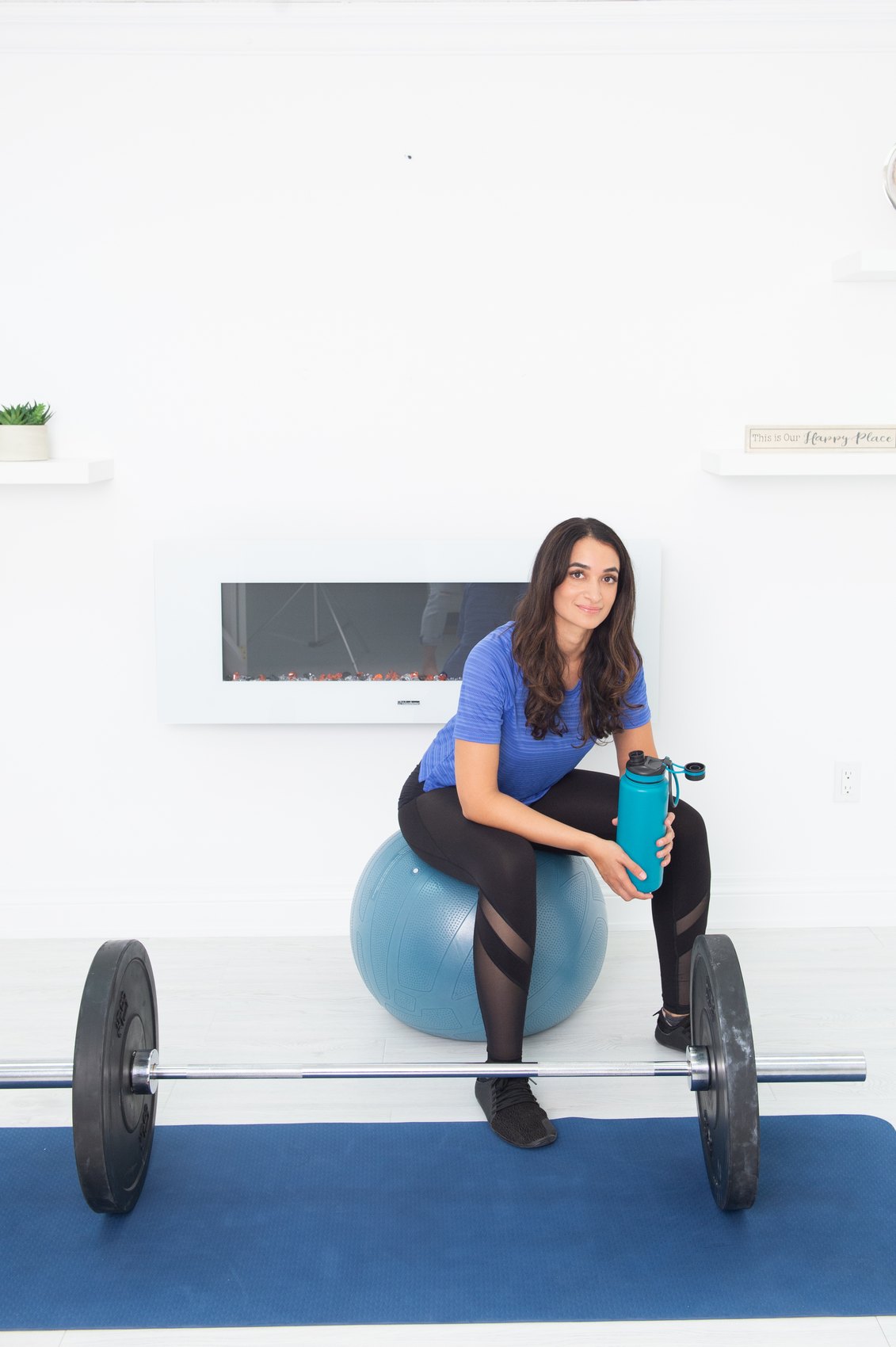Salwa Qadir seated with a barbell and stability ball