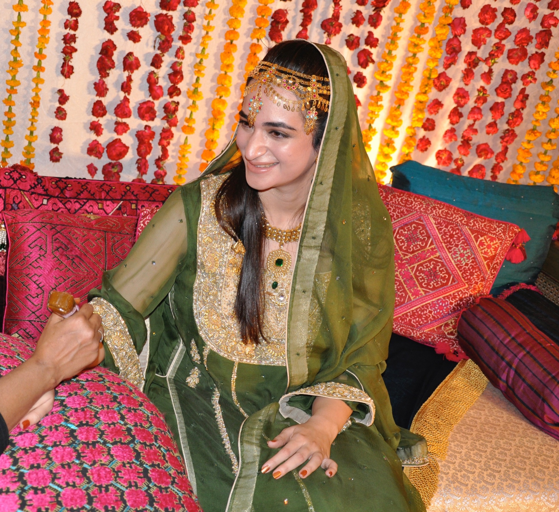 Salwa Qadir wearing a green wedding outfit surrounded by colourful flowers