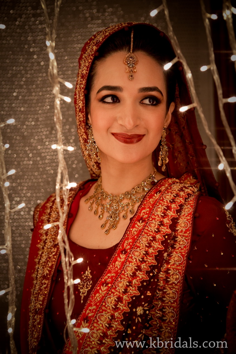 Salwa Qadir wearing a red wedding outfit framed by warm lights